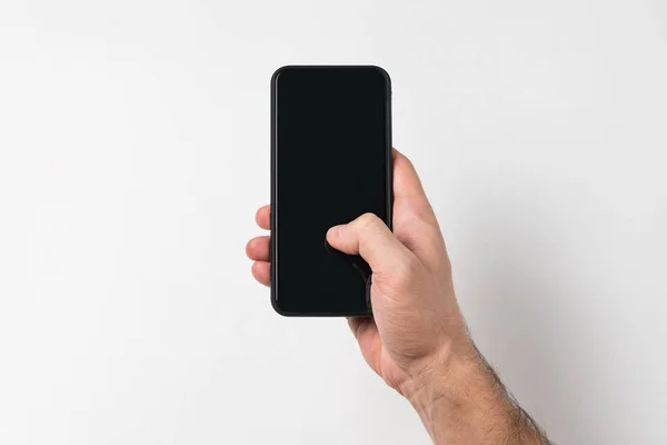 Smartphone en mano masculina dedo en la pantalla. Fondo blanco. Pantalla en blanco. Copiar espacio — Foto de Stock