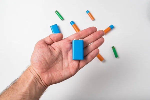 Batteria blu PP3 in mano maschile su sfondo bianco. Diversi tipi di accumulatori . — Foto Stock