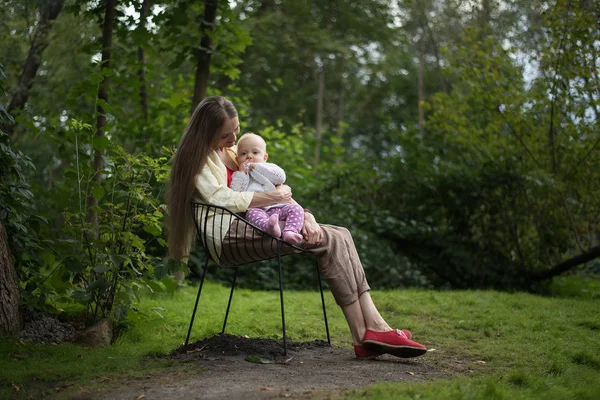 Jeune mère reposant sur une chaise avec bébé sur fond de nature. Séjour avec enfant à Park — Photo