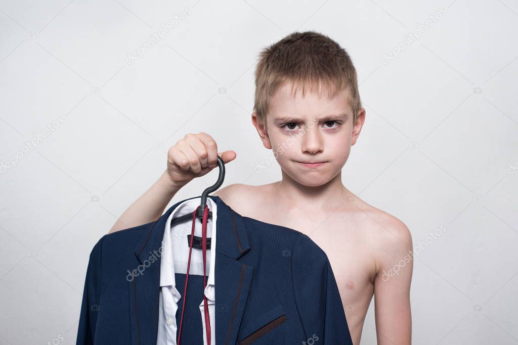 Unhappy child boy holds a business suit, school uniform. Young business boy is going to work