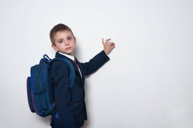 Sırt çantası tahtada yazan okul üniformalı ciddi bir öğrenci. Yarım boy portre, beyaz arka plan. Boşluğu kopyala
