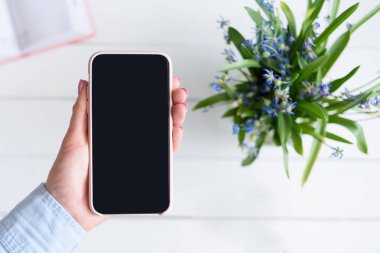 Bitki arka planında modern akıllı telefondan el ele tutuşmak. Boşluğu kopyala