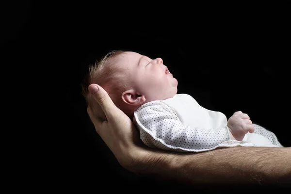 Den sovande blonda babyn ligger på en mans hand. Svart bakgrund — Stockfoto