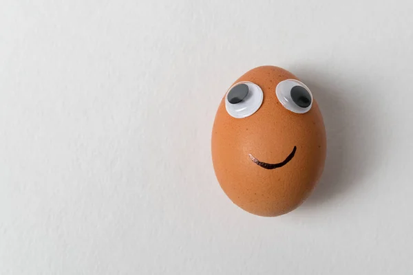 Huevo divertido con ojos grandes sobre fondo blanco. Huevo con ojos y sonrisa . — Foto de Stock