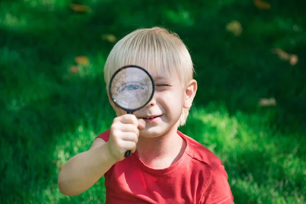 Junge mit Lupe im Freien. Vision für die Untersuchung. — Stockfoto