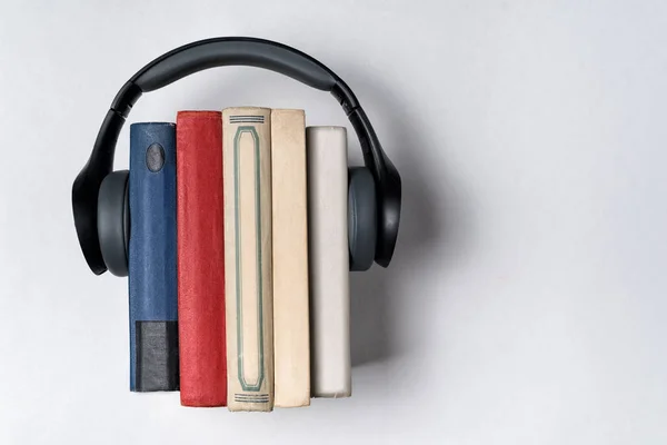 Słuchawki noszone na stosie książek w białym tle. Literatura w formacie audio. Koncepcja audiobooka — Zdjęcie stockowe