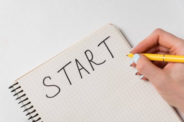 Başlat yazıtlı defter. Kapatın. Beyaz arkaplanda not defterine kadın el yazısı.