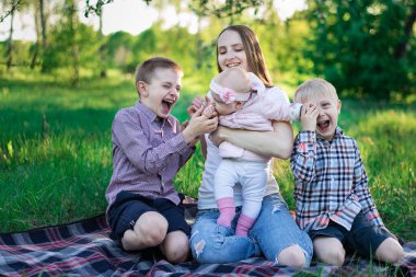 Oğulları ve küçük kızı olan bir anne doğayla eğleniyor. Mutlu aile yaz parkında piknik yapar.