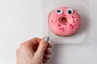 Kadın eli ve plastik kaplarda kocaman gözleri olan komik bir çörek. ekoloji kavramı.