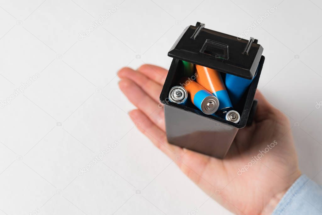 Used batteries in the trash in female hand. High danger for the environment. Proper disposal of batteries and accumulators.