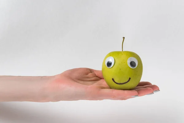 Słodkie Małe Jabłko Zabawną Twarzą Spoczywa Dłoni Białe Tło — Zdjęcie stockowe