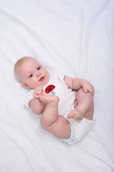 Bebé Sonriente Con Pañal Acostado Sábanas Blancas Chico Toca Sus — Foto de Stock
