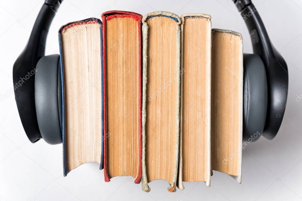 Old books and headphones on a white background closeup. Audio books concept. Top view.