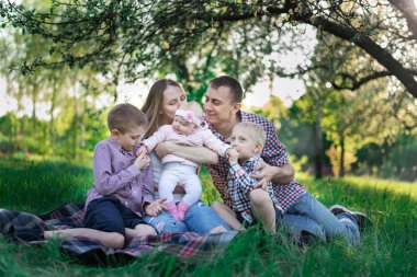 Aile parkta harika vakit geçiriyor. Baba oğluna sarılıyor. Doğada mutlu bir aile