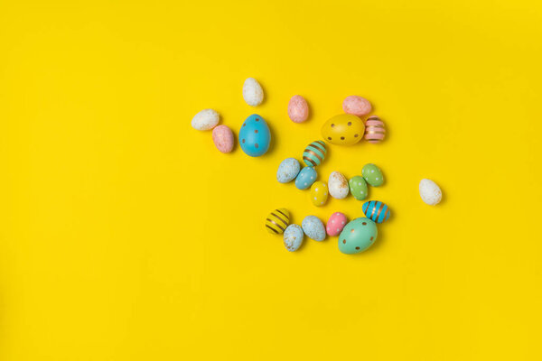 Colorful Easter eggs on yellow background. Top view of festive eggs