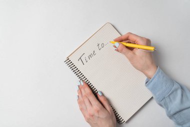Not defterinde beyaz arkaplana dikkat çekme zamanı. El yazısıyla yazılmış kelimeler. Beyaz arkaplanda kadın eli ve defter.