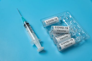 Aşı COVID-19 ve şırınga ile ampul paketleme. Mavi arka plan. Tıbbi konsept