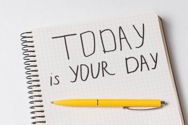 Not Defteri 'ndeki motivasyon yazıtları bugün senin günün. Defter ve kalemi yakın plan çek. El yazısı.