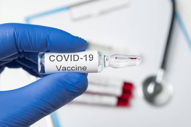 Coronavirus için ampul aşısı olan azot eldivenli doktor. Etiketi Covid-19 olan şişe.