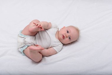 Yeni doğmuş bebek beyaz çarşaflarda uyuyor. Küçük kızın yatakta uzanmış şirin portresi..