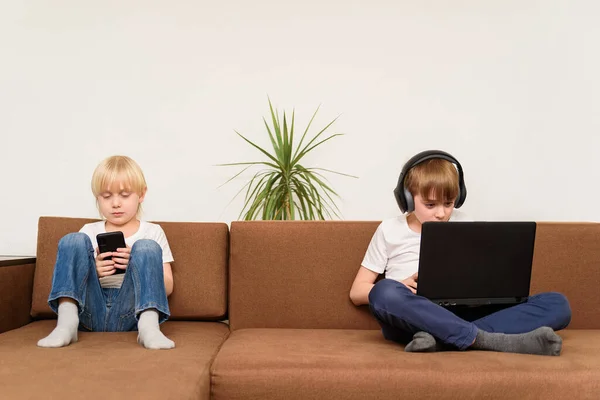 Två Barn Sitter Soffan Med Prylar Smartphone Och Bärbar Dator — Stockfoto