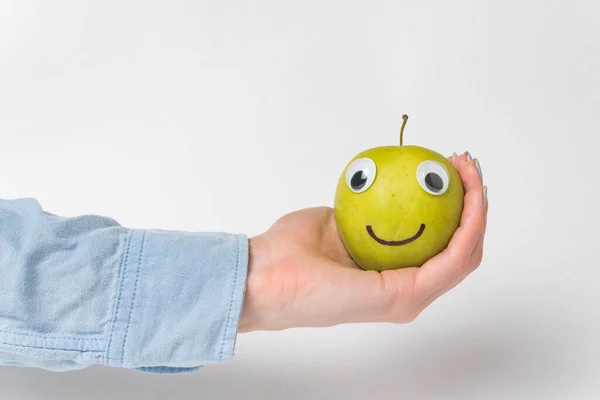 Ręka Trzyma Zielony Apple Smiley Google Oczy Śmieszne Jabłko Białym — Zdjęcie stockowe