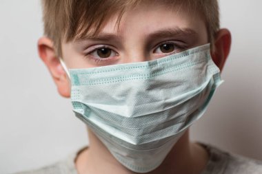 Çocuk Coronavirus 'tan korunmak için koruyucu tıbbi maske takıyor. Yüzünde sağlık maskesi olan bir çocuk.