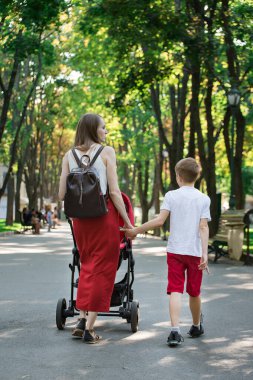 Anne ve oğlu Park 'ta el ele tutuşarak yürüyor. Dikey çerçeve.