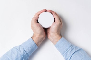 Erkek eller beyaz kozmetik kavanozu maketini tutuyor. beyaz arkaplan üst görünümü.