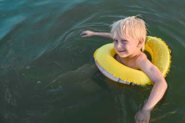 Sarı lastik yüzükle yıkanan sarışın çocuk. Çocuğa yüzmeyi öğret. .