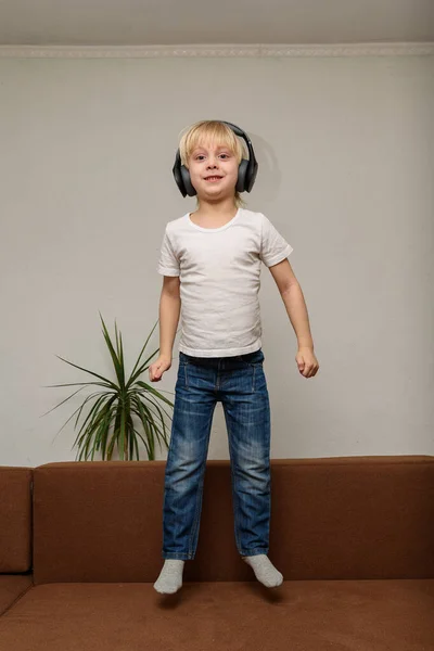 Шестилетний Ребенок Слушает Музыку Прыгает Диване Вертикальная Рамка — стоковое фото
