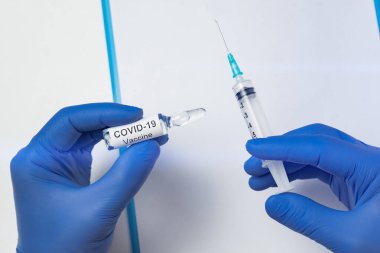 Mikrobiyolog elinde şırınga ve ampul ile koronavirüs aşısı tutuyor. Covid-19 bulaşıcı hastalıklar.