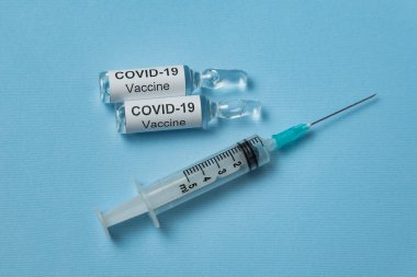 Covid-19 etiketli aşı ve mavi arka planda şırınga enjeksiyonu. 2019-nCoV bulaşıcı hastalığın tedavisi.