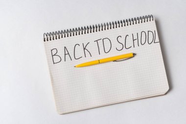 Not defterindeki el yazısı ilanı okula geri döndü. Beyaz arkaplan, üst görünüm.