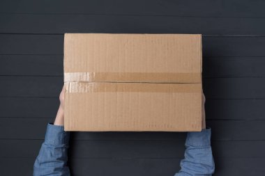 Çocuk eller büyük bir karton kutu tutuyor. Eve paket teslimatı. Üst görünüm.