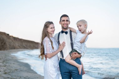 Denizde küçük oğlu olan genç bir aile. Çocuklarla birlikte denizde tatil. Deniz kenarındaki yazın tadını çıkarıyorum.