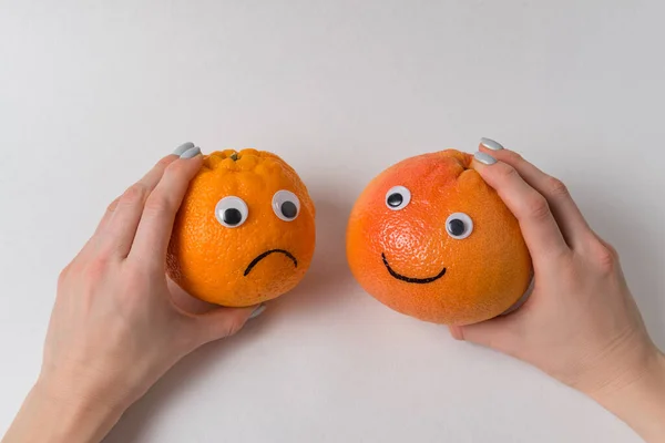 Manos Sosteniendo Naranja Pomelo Con Caras Divertidas Sobre Fondo Blanco — Foto de Stock