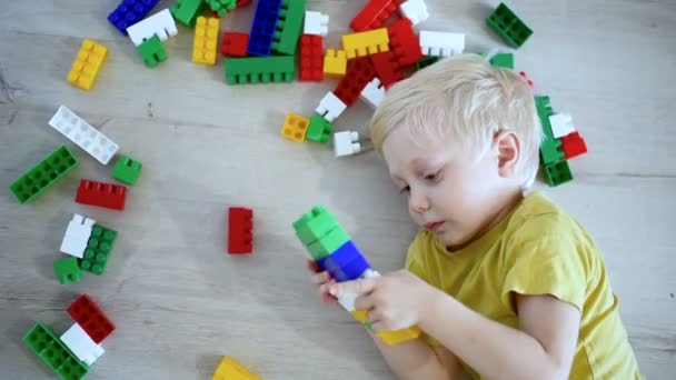 Blond boy lies on the floor among the designer. Top view — Stock Video