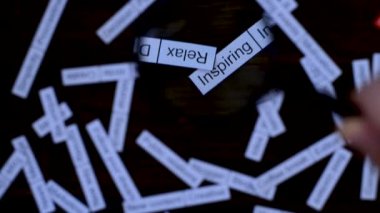 Büyüteçle el, cümle aramasına odaklanır. Çözüm bulmak. Koyu tahta masada etiket bulutu.