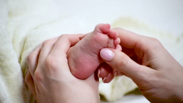 Kadın eli, bebeğin ayağına masaj yapar. Bakım ve annelik. Yakın plan. — Stok video