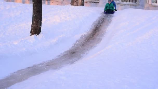 Kind Auf Plastikschlitten Fährt Winter Vom Verschneiten Hügel Herunter Junge — Stockvideo