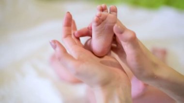 Annem bebeğin ayaklarına hafifçe dokunuyor. Kadın bebek için dokunaklı ayak masajı yapıyor. Kapat..