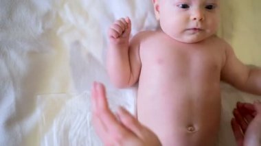 Kadınsı eller masaj bebeği. Çocukların karnını okşuyor. Anne bebeğe dokunuyor,