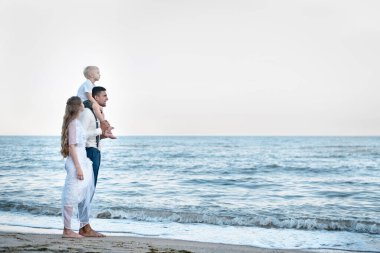 Okyanusta yürüyen birbirine aşık güzel bir çift. Küçük çocukla seyahat et. Mutlu ebeveynlik.