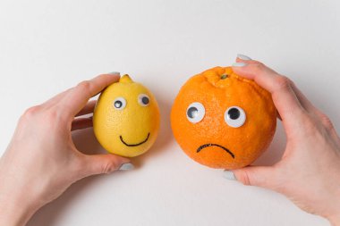 Elleri limonlu ve portakallı. Beyaz arka planda komik suratlı yemekler..