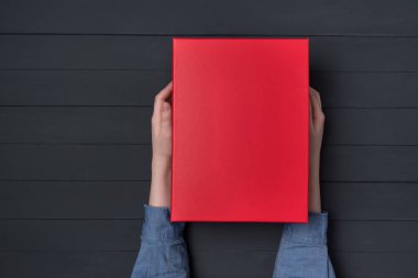 Çocukların elinde kırmızı bir hediye kutusu var. Siyah arka plan. Üst görünüm