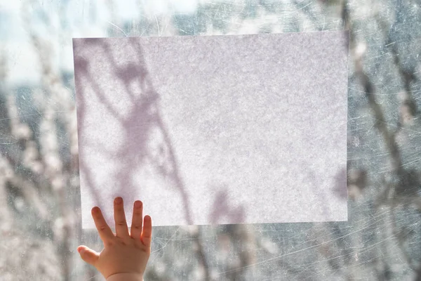 Mano Los Niños Sostiene Una Hoja Blanca Papel Vidrio Ventana —  Fotos de Stock