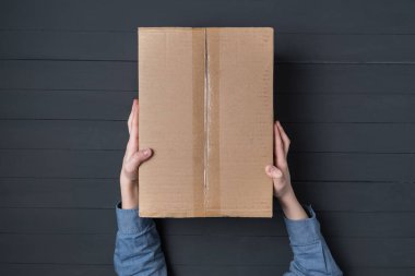 Çocuk eller büyük bir karton kutu tutuyor. Eve paket teslimatı. Üst görünüm.