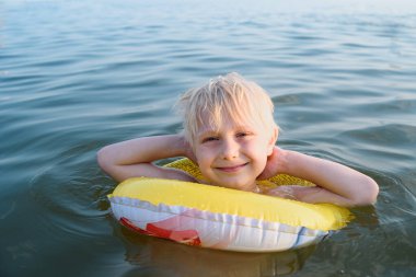 Lastik yüzükle yüzen sevimli sarışın çocuk. Sudaki çocuğun güvenliği