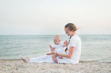 Kumsalda oturan mutlu bir anne ve küçük bir çocuk. Annelik ve bakım.